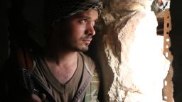 A rebel fighter looks through a hole in the wall as he holds a position on February 19, 2014 in the northern Syrian city of Aleppo.