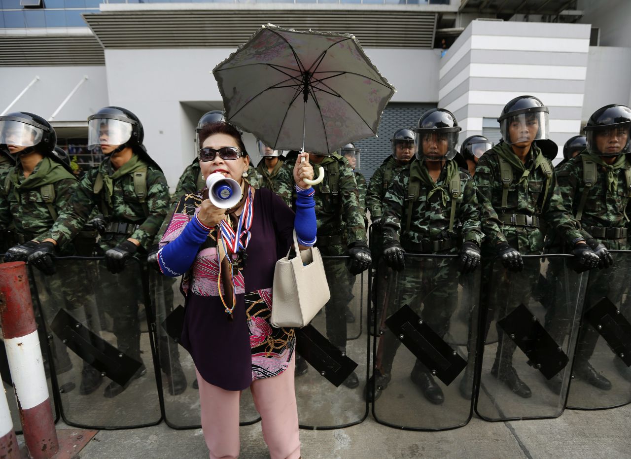 A protester shouts slogans in front of Thai army soldiers on guard during a rally in front of the temporary office of the prime minister at the defense ministry complex in Bangkok on Wednesday, February 19.