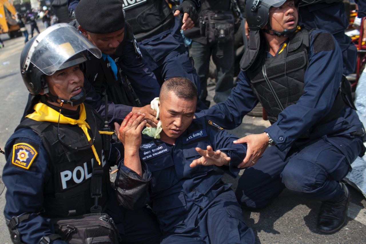 Police officers assist a colleague who was injured by a grenade thrown by protesters in Bangkok on Tuesday, February 18. At least five people were killed and more than 70 were injured in clashes <a href="http://www.cnn.com/2014/02/17/world/asia/thailand-protests/index.html">during a police crackdown</a>.