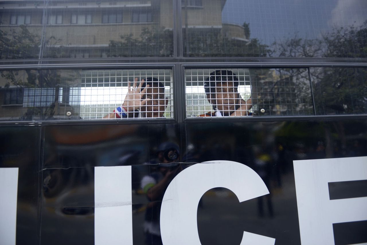 Two protesters who were arrested are taken away in a police van after clashes at Phan Fah Bridge in Bangkok on February 18. Thai police tried to reclaim the area, which anti-government protestors had been occupying for weeks, but were eventually forced to retreat after a grenade explosion and sporadic gunfire.