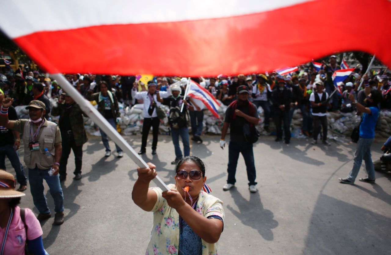 Protesters wave flags during a standoff with riot police in Bangkok on February 18.