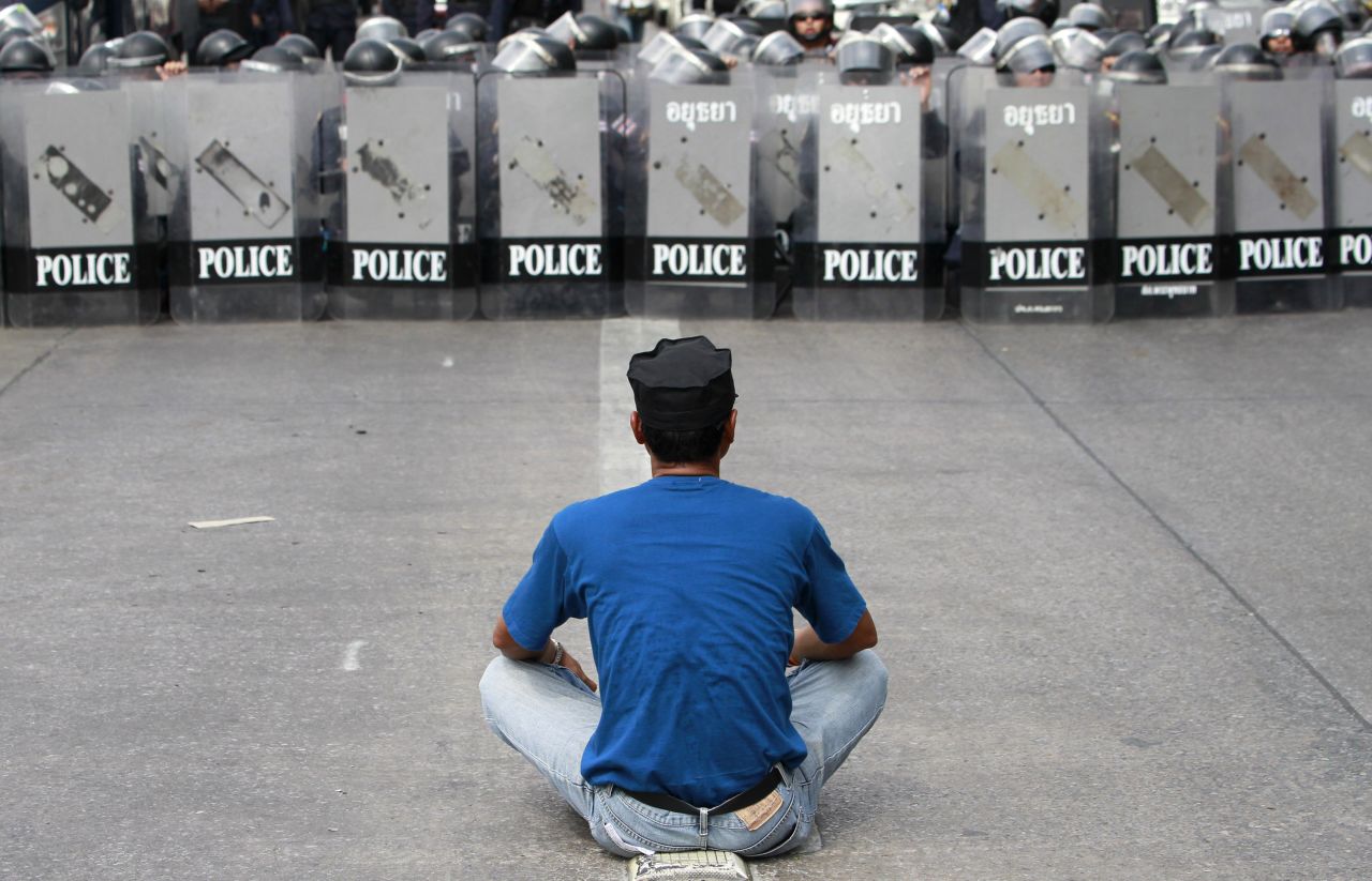 A demonstrator sits in front of a row of riot police during an operation to reclaim government offices occupied by protesters in Bangkok on February 14. The attempted evictions led to a flare-up of violence after a period of relative calm.