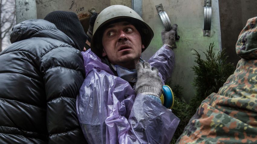 An anti-government protester takes cover from suspected sniper fire near the Hotel Ukraine on February 20, 2014 in Kiev, Ukraine. 