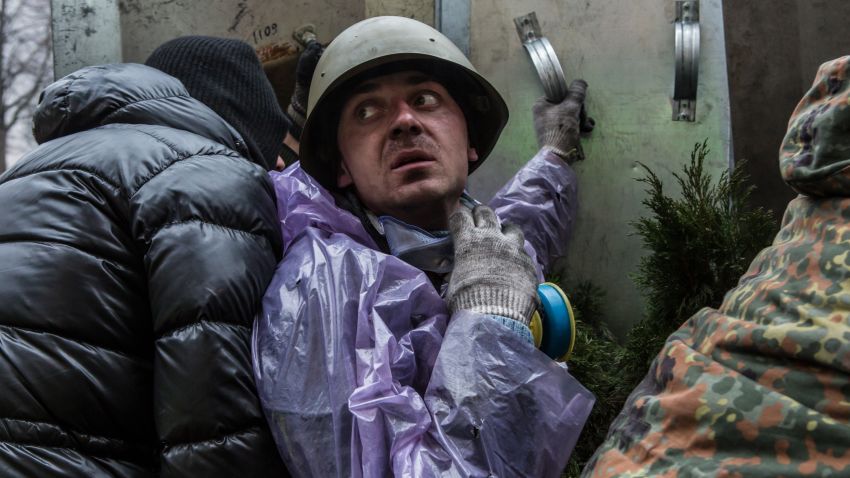 An anti-government protester takes cover from suspected sniper fire near the Hotel Ukraine on February 20, 2014 in Kiev, Ukraine.