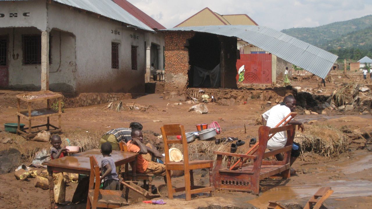 A familly sits outside their destroyed house, on February 11 in Bujumbura, after flooding and landslides caused by a night of torrential rain swept away hundreds of homes and killed at scores of people.