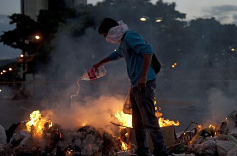 A protester adds fuel to a fire during clashes with police in Caracas on February 20.