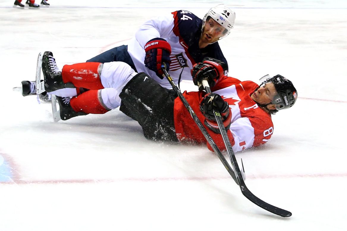 America's Brooks Orpik, top, and Canada's Sidney Crosby fall to the ice during their semifinal game.