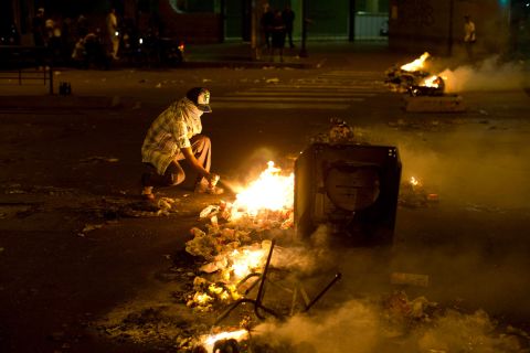 A masked protester sprays a flammable substance on a barricade during protests in Caracas on February 21.