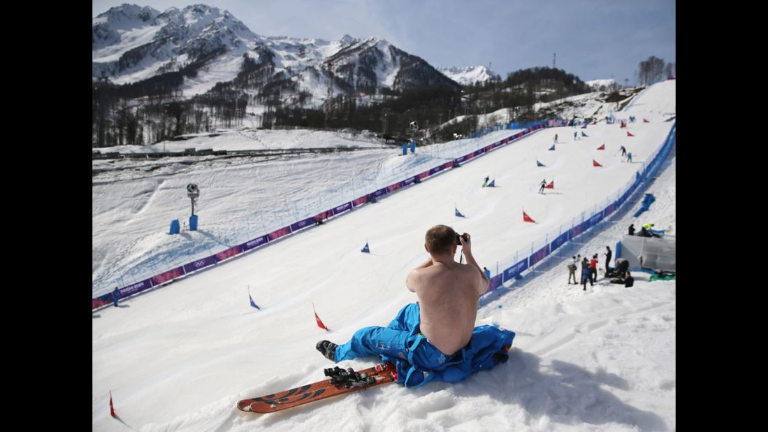 A course worker takes his shirt off to enjoy warm weather during the snowboard parallel slalom competition on February 22.