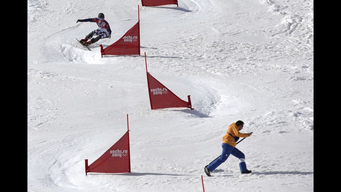 Russia's Vic Wild takes a turn as a course worker runs to get out of the way during a the snowboard parallel slalom quarterfinal on February 22.