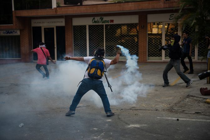Manifestantes devuelven gases lacrimógenos a la policía.