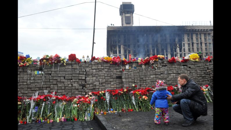 A man and his daughter lay flowers at a memorial for protesters killed in Independence Square. 
