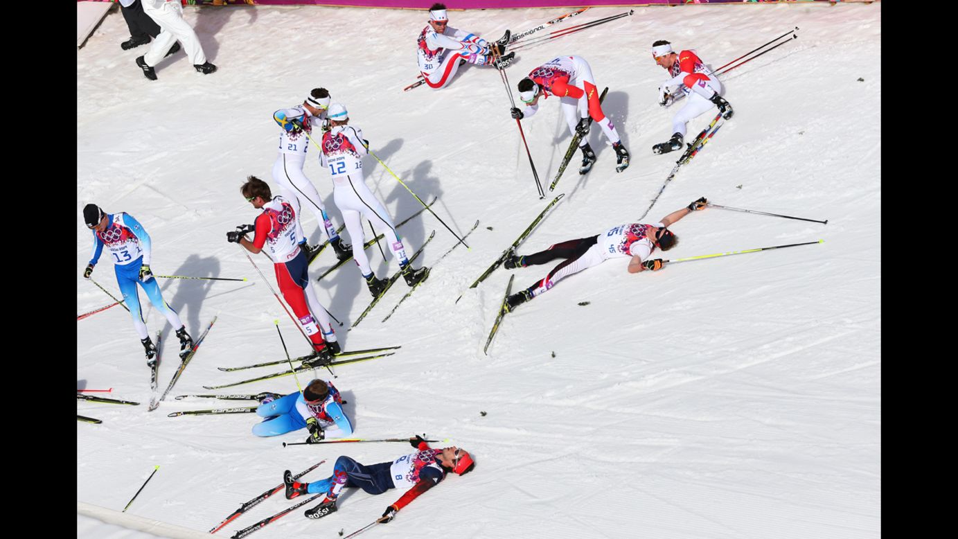 Skiers collapse on the snow after the men's 50-kilometer mass start free on February 23.