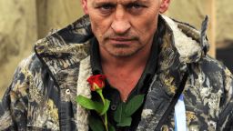 A man brings a rose to a memorial to the anti-government protesters killed durign the past weeks' clashes with riot police in Kiev's Independence Square on February 23, 2014.