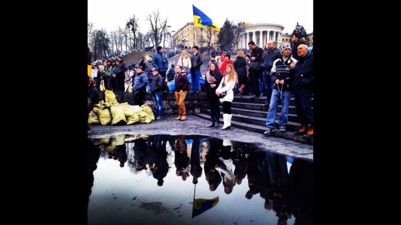 KIEV, UKRAINE:  Ukrainians are reflected in a puddle as they gather to mourn the dead in Maidan Square on February 23, after protesters succeeded in forcing President Viktor Yanukovich out of office.  Photo by CNN's Christian Streib.  Follow Christian on Instagram at <a href="https://trans.hiragana.jp/ruby/http://instagram.com/christianstreibcnn" target="_blank" target="_blank">instagram.com/christianstreibcnn</a>.