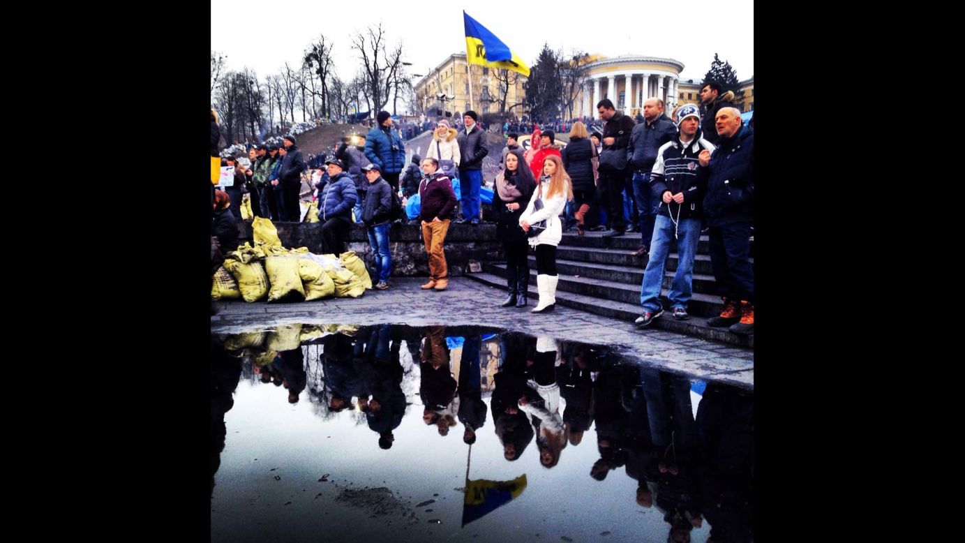 KIEV, UKRAINE:  Ukrainians are reflected in a puddle as they gather to mourn the dead in Maidan Square on February 23, after protesters succeeded in forcing President Viktor Yanukovich out of office.  Photo by CNN's Christian Streib.  Follow Christian on Instagram at <a href="http://instagram.com/christianstreibcnn" target="_blank" target="_blank">instagram.com/christianstreibcnn</a>.
