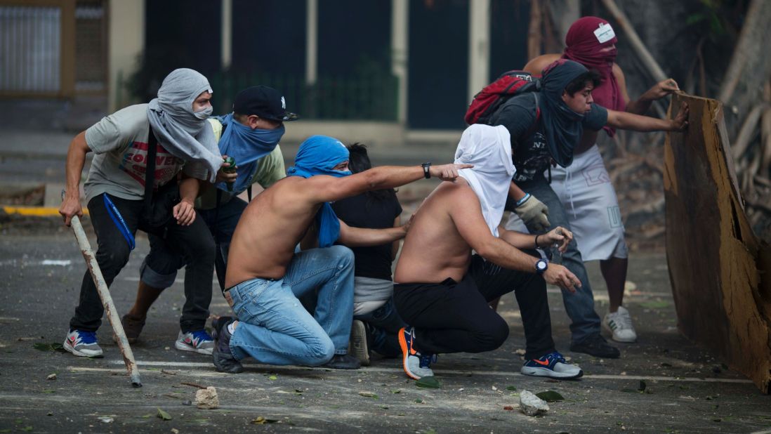Anti-government protesters take cover during clashes with riot police in Caracas on February 22.