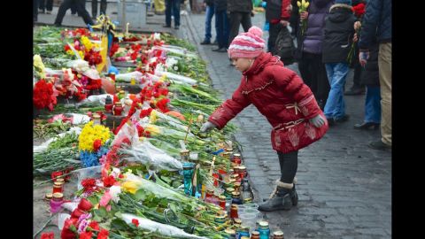 KIEV, UKRAINE:  A young girl pays tribute to anti-government protesters killed in the clashes with riot police by placing a flower on a makeshift memorial leading to the barricades in central Kiev on February 24.  Photo by CNN's Todd Baxter.