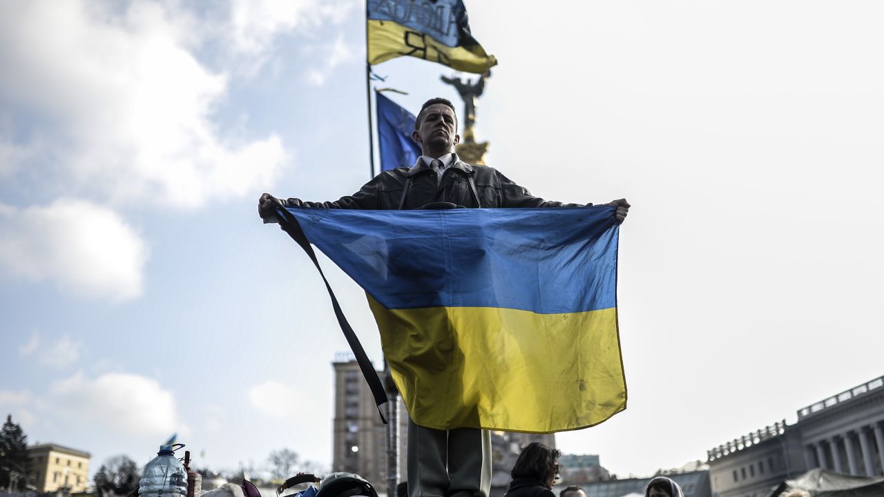 A man holds a Ukrainian flag as he stands on Kiev's Independence Square on February 24, 2014. Ukraine issued an arrest warrant Monday for ousted president Viktor Yanukovych over the 'mass murder' of protesters and appealed for $35 billion in Western aid to pull the crisis-hit country from the brink of economic collapse. The dramatic announcements by the ex-Soviet nation's new Western-leaning team -- approved by parliament over a chaotic weekend that saw the pro-Russian leader go into hiding -- came as a top EU envoy arrived in Kiev to buttress its sudden tilt away from Moscow. AFP PHOTO/ BULENT KILIC (Photo credit should read BULENT KILIC/AFP/Getty Images)