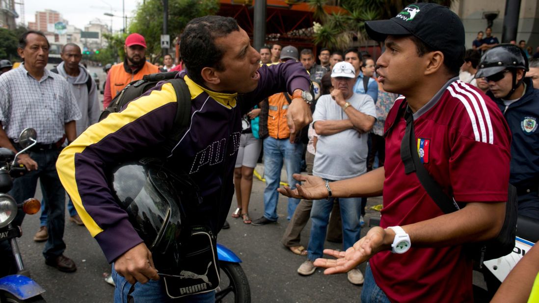 A motorcyclist, left, argues with demonstrators blocking a highway in Caracas on February 24.
