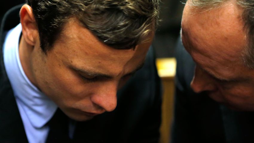 Oscar Pistorius (L) speaks with his lawyer Kenny Oldwage prior to an indictment hearing on August 19, 2013 in Pretoria, South Africa.