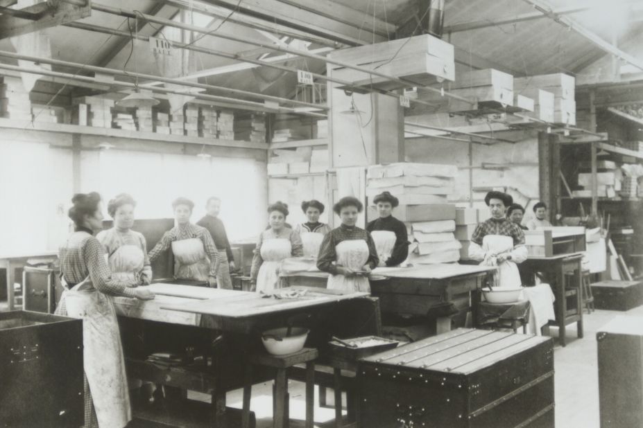 Here, a group of workers is photographed inside the workshop in 1909. The company's long history has been inextricably linked to travel, and Vuitton trunks were designed with a flat top to fit the modern requirements of mass-journeys by train and steamboat. 