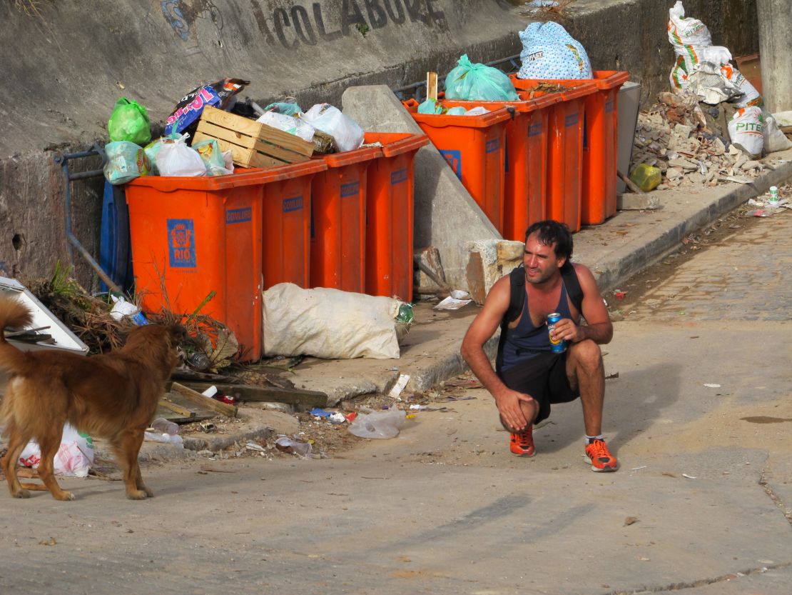 A tourist in Rio's Vidigal favela calls to a dog on a street.