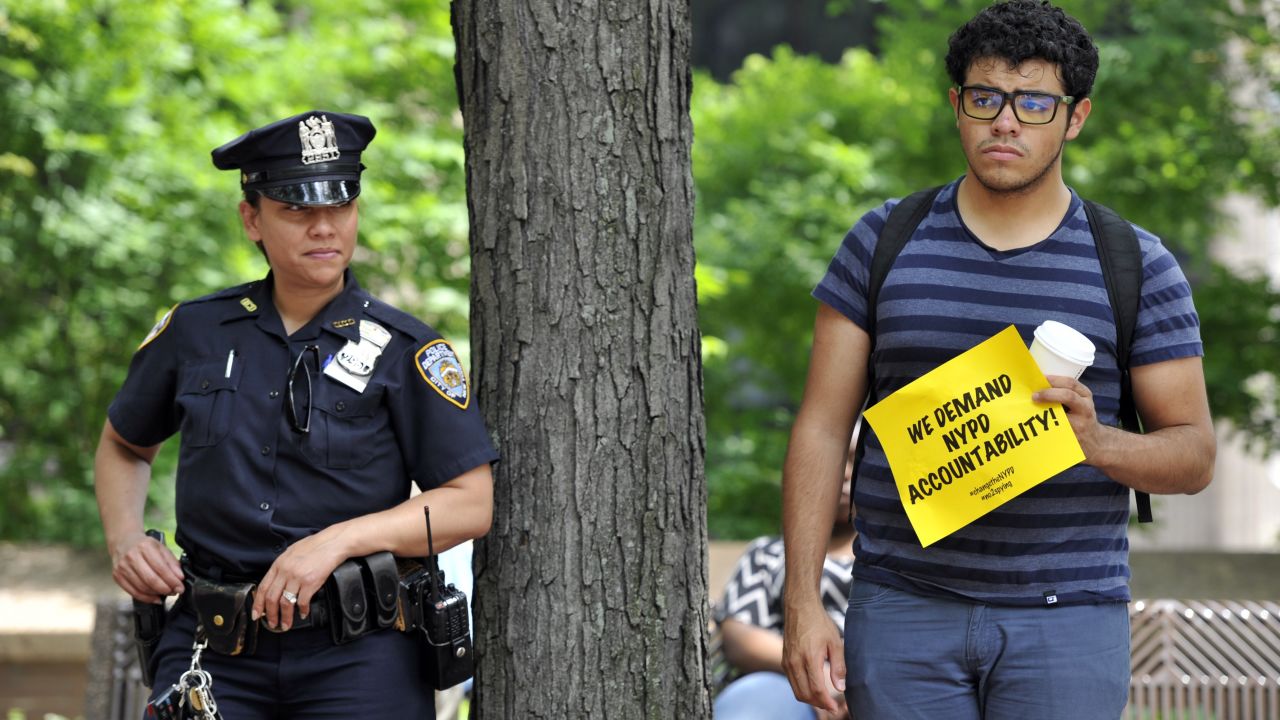 An NYPD officer and a protester look on as advocates and residents hold a press conference June 18, 2013, in New York  to discuss legal action challenging surveillance of businesses frequented by Muslim residents and of mosques.  