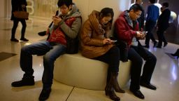 In a photo taken on November 27, 2013 people use their mobile phones as they sit inside a shopping mall in Beijing. China's new free-trade zone has drawn just 38 overseas firms in its first two months of operations, officials said, as foreign companies await concrete policies and deeper reforms. AFP PHOTO / Ed Jones (Photo credit should read ED JONES/AFP/Getty Images)