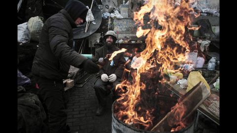 A man adds fuel to a fire at a barricade in Independence Square on February 27. Dozens of people were killed during clashes between security forces and protesters.