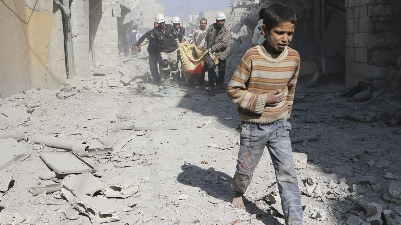 Un niño camina delante de los hombres que llevan el cuerpo de su madre en Alepo, Siria, el sábado 22 de febrero. Según los activistas, la mujer fue asesinada cuando fuerzas leales al presidente sirio Bashar al-Assad arrojaron barriles explosivos. 