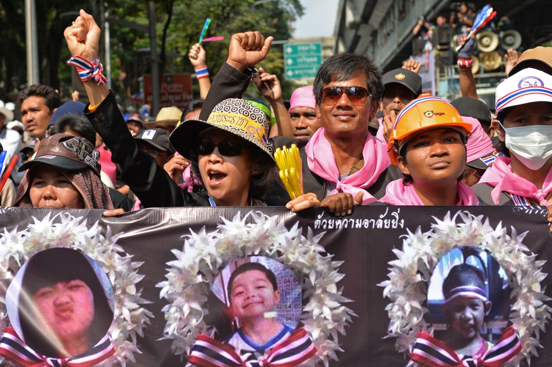 Anti-government protesters march holding posters of child victims of a recent bomb blast in Bangkok. 