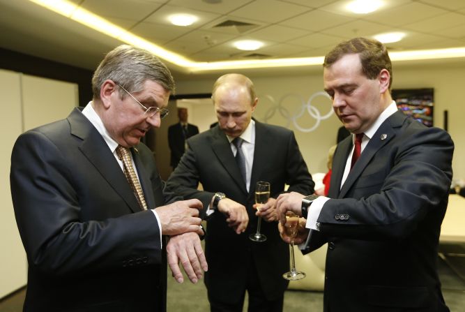 From left, International Olympic Committee President Thomas Bach, Russian President Vladimir Putin and Russian Prime Minister Dmitry Medvedev look at their watches before the <a href="http://www.cnn.com/2014/02/23/world/gallery/olympic-closing-ceremony/index.html">closing ceremony</a> of the Winter Olympics on Sunday, February 23, in Sochi, Russia.