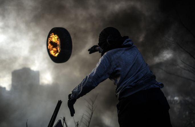 An anti-government demonstrator throws a burning tire as he builds a barricade Friday, February 21, at Independence Square in Kiev, Ukraine.