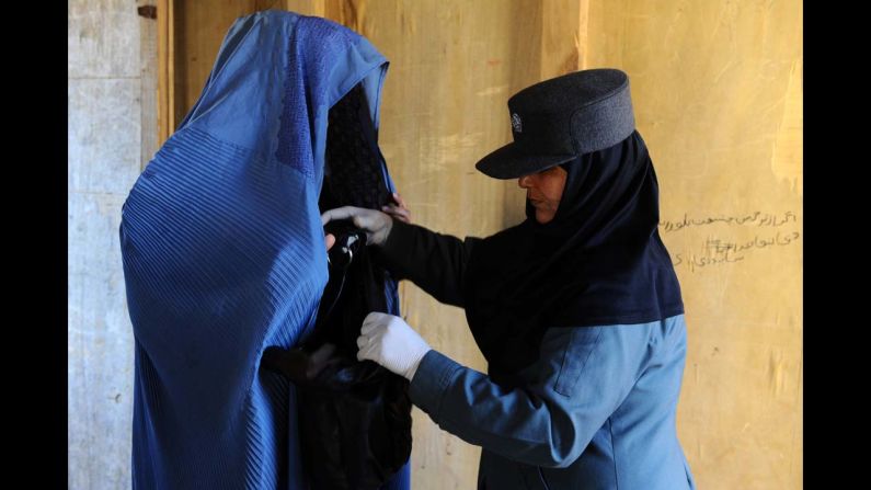 An Afghan policewoman searches a burqa-clad resident at a voter registration center in Herat province on Wednesday, February 26. Afghanistan is due to hold elections in April.