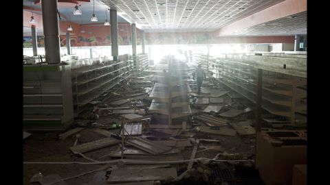 An employee of a supermarket in Maracay, Venezuela, inspects the damage done by looters on February 26.