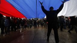 Pro-Russian demonstrators march with a huge Russian flag during a protest in front of a local government building in Simferopol, Crimea, Ukraine, Thursday, Feb. 27, 2014. Ukraine's acting interior minister says Interior Ministry troops and police have been put on high alert after dozens of men seized local government and legislature buildings in the Crimea region. The intruders raised a Russian flag over the parliament building in the regional capital, Simferopol, but didn't immediately voice any demands. (AP Photo/Darko Vojinovic)