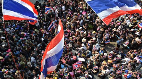 Travelers to Bangkok are advised to look up and avoid all potential protest sites. In this photo: Anti-government protesters wave Thai flags outside the national police headquarters on February 26. 