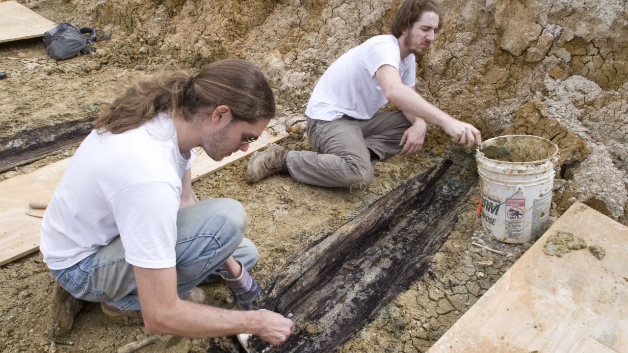 Derek Anderson and Forrest Follett remove the soil from the lid of one the graves.