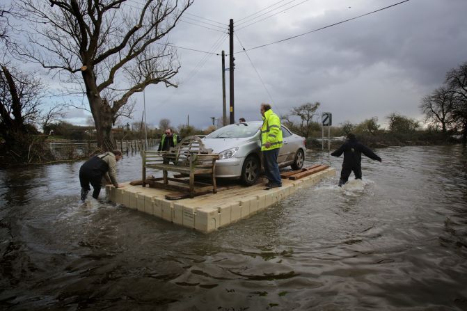 Volunteers use a pontoon to move a car that has been cut off by floodwaters in Somerset, England, on Thursday, February 27.
