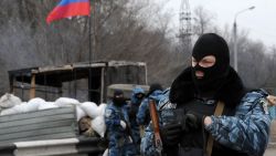 Armed masked men who call themselves members of Ukraine's disbanded elite Berkut riot police force stand at their checkpoint under a Russian flag on a highway that connect Black Sea Crimea peninsula to mainland Ukraine near the city of Armyansk, on February 28, 2014. The spiralling tensions in a nation torn between the West and Russia took today a severe new turn when Ukraine's interim president Oleksandr Turchynov accused Russian soldiers and local pro-Kremlin militia of staging raids on Crimea's main airport and another base on the southwest of the peninsula where pro-Moscow sentiments run high.