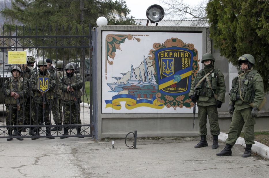 Ukrainian soldiers, left, and unidentified gunmen, right, stand at the gate of an infantry base in Perevalne on March 2. 