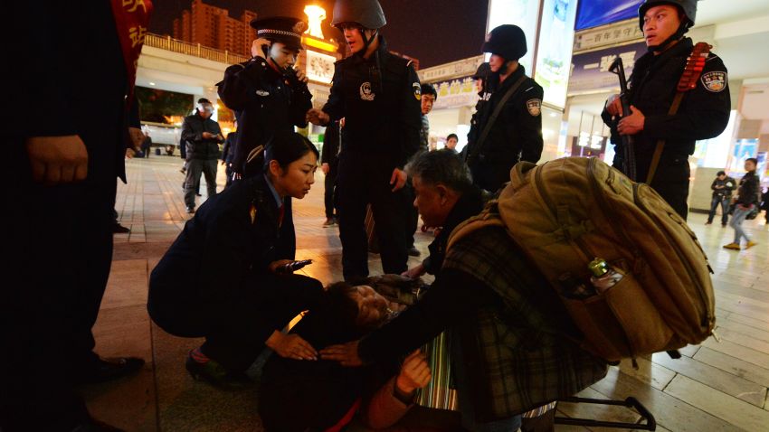 Chinese armed police and officials help a sick woman at the scene of the terror attack at the main train station in Kunming, Yunnan Province on March 2, 2014. Knife-wielding assailants left at least 29 people dead and more than 130 wounded in an unprecedented attack at a Chinese train station, with state media blaming separatists from Xinjiang. Victims described attackers dressed in black bursting into Kunming station in the southwestern province of Yunnan and slashing indiscriminately as people queued to buy tickets, prompting shock and outrage. AFP PHOTO/Mark RALSTON (Photo credit should read MARK RALSTON/AFP/Getty Images)