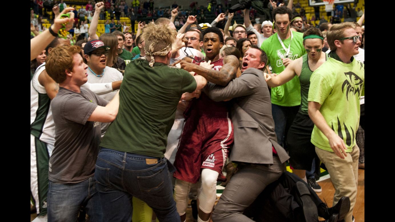 New Mexico State's Daniel Mullings, center, is caught up in a brawl involving players and fans after the game at Utah Valley on Thursday, February 28. The melee started after New Mexico State guard K.C. Ross-Miller hurled the ball at Utah Valley's Holton Hunsaker seconds after Utah Valley's 66-61 overtime victory.