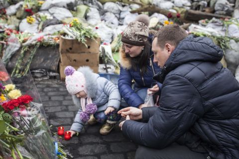 A young family lights candles in memory of those who died protesting in Maidan Nezalezhnosti, the central square of Kiev. 