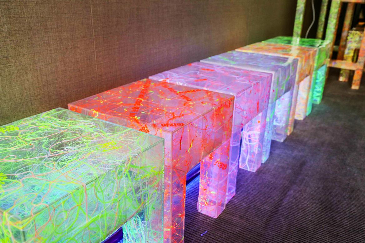Artist Lee Eunsook feels that modern society hinders communication and creates stress. Her benches and chairs are made of hundreds of small polyester chairs and illuminated with black light.