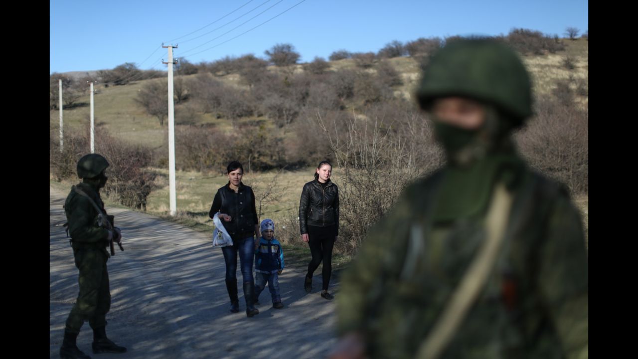 Wives of Ukrainian soldiers walk past Russian soldiers to visit their husbands guarding a military base in Perevalne on March 3.