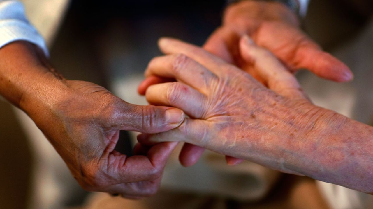 A home health aide massages the fingers of a woman in her care. Olympia Dukakis says home care workers are indispensable.