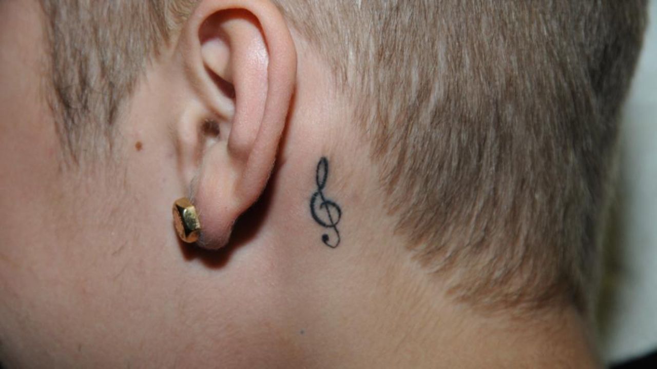A tattoo of a musical symbol rests behind Bieber's ear. 