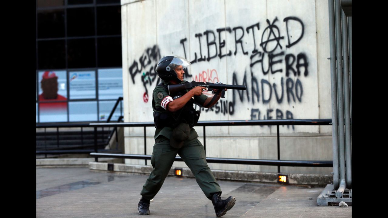 A National Guard officer points a tear gas launcher at demonstrators in Caracas on March 4.